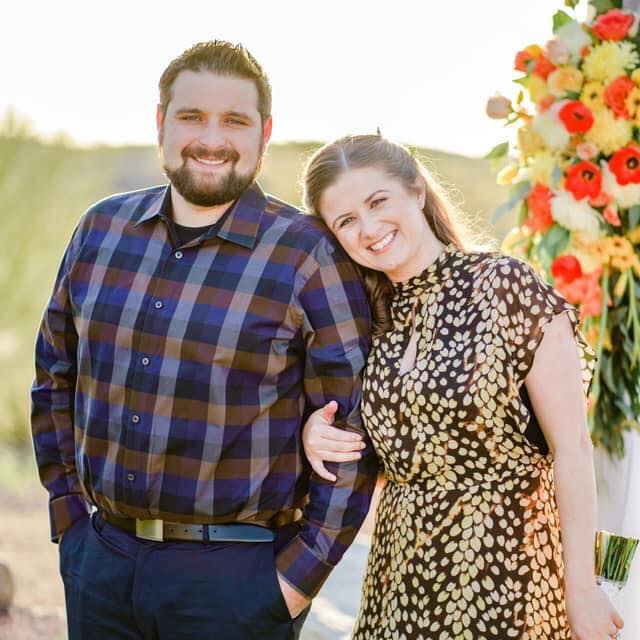 Couple smiling at outdoor wedding event.