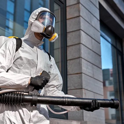 Person in hazmat suit with sprayer outdoors