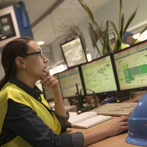 Female engineer analyzing data on multiple computer screens.
