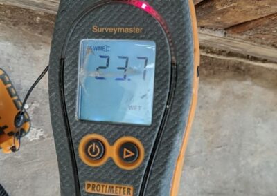 Moisture meter reading high wetness on wood surface.