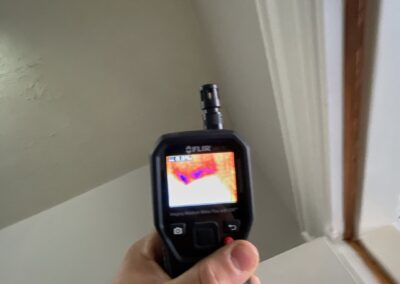 Hand holding a thermal imaging camera indoors.