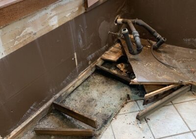 Kitchen renovation with exposed pipes and removed cabinets.