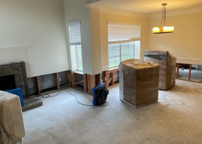 Empty room under renovation with fireplace and ceiling fan.