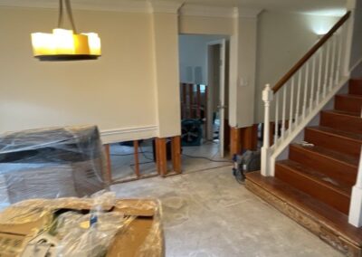 Interior home renovation with staircase and protected furniture.