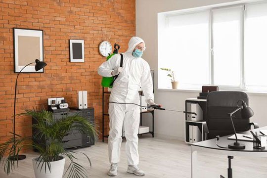 Person in hazmat suit sanitizing office space.